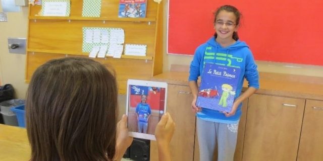 Élèves qui se fait filmer en présentant un livre