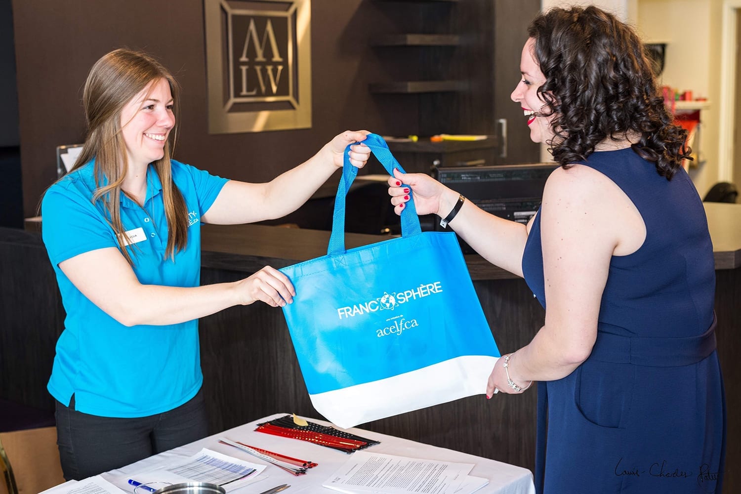Une organisatrice d'évènement remet un sac promotionnel à une participante