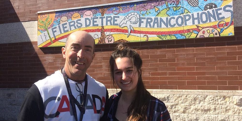 Homme et jeune femme posant devant une école