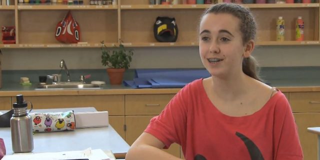 Jeune fille parlant à la caméra devant un atelier d'arts plastiques