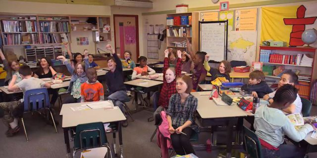 Groupe de niveau élémentaire avec un drapeau d'Inuksuk en arrière plan dans une salle de classe
