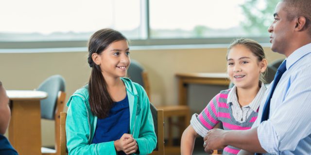 Un membre du personnel scolaire discute avec deux jeunes étudiantes
